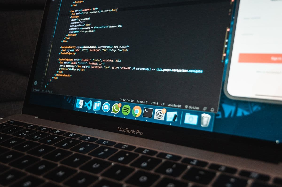 A laptop on a dark desk with a code editor open on its screen